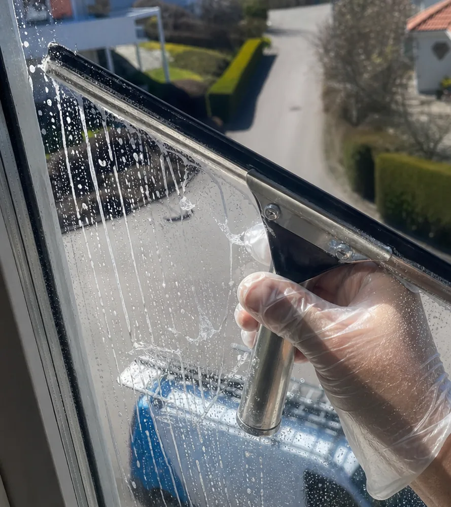 Fönsterskrapa på en våt glasruta