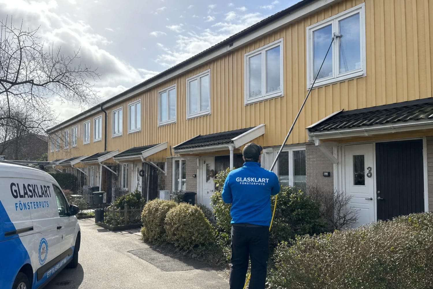Fönsterputsare från Glasklart putsar fönster på en radhuslänga med vattenmatat skaft