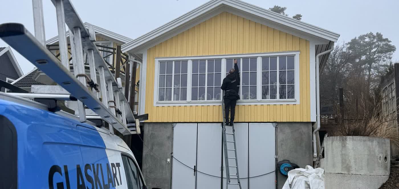 Fönsterputsare arbetar utvändigt vid en svensk flerbostadsfastighet
